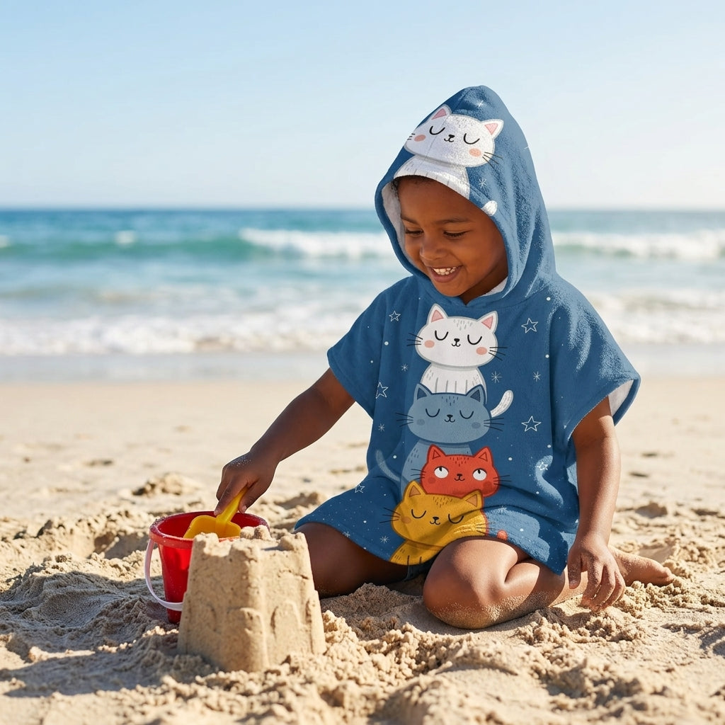 Kind met MiniCat kinderponcho met capuchon op het zand bij zee