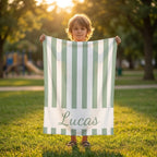 Child holding personalised striped beach towel with name, custom microfibre towel for kids