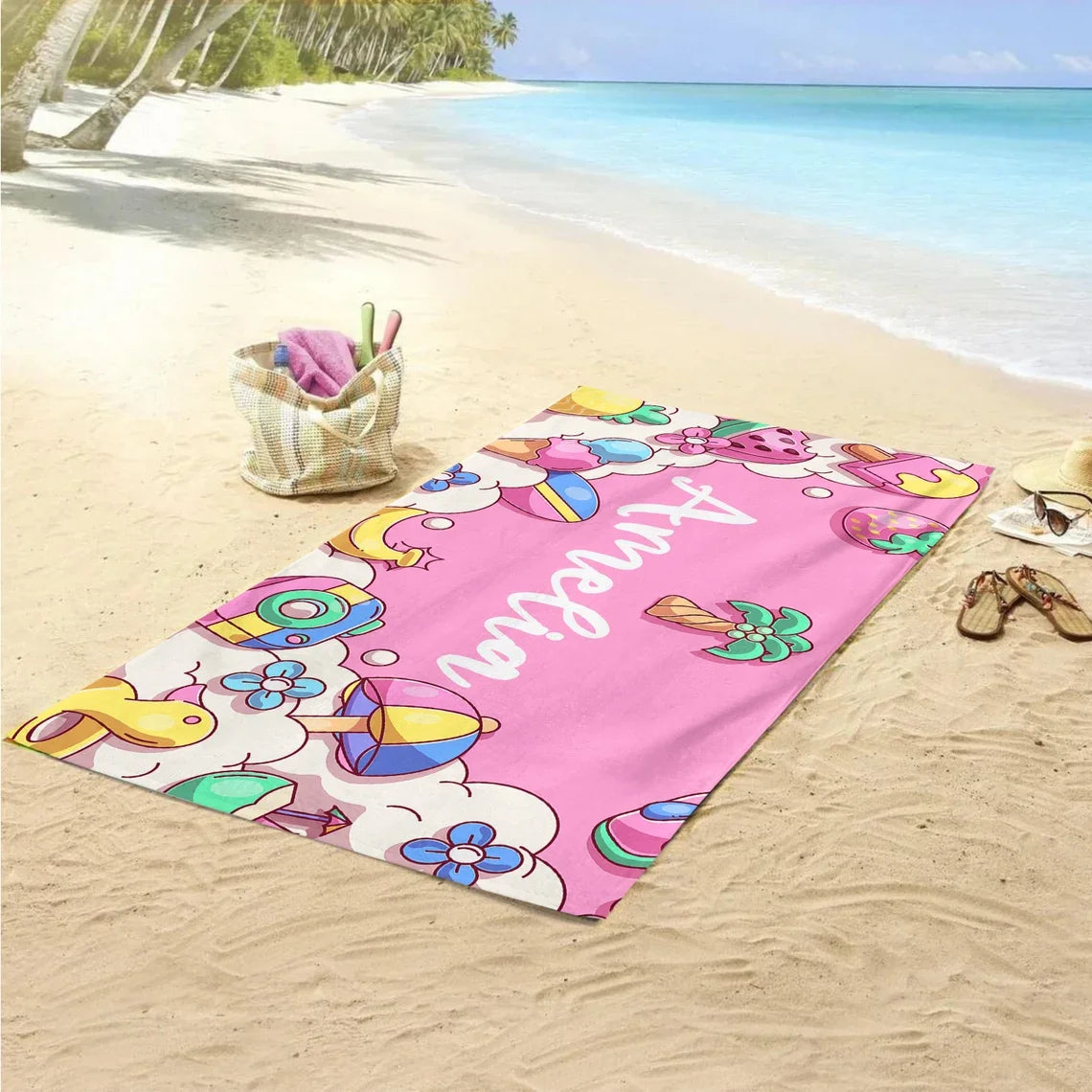 Personalised kids beach towel laid on sand with colourful design and custom name