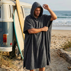Middernacht Zwarte BeachFlow poncho met capuchon bij een busje op het strand
