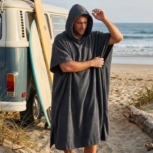 Middernacht Zwarte BeachFlow poncho met capuchon bij een busje op het strand