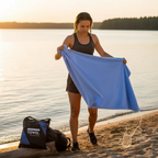 Woman holding blue oversized microfibre beach towel on beach, lightweight quick dry towel